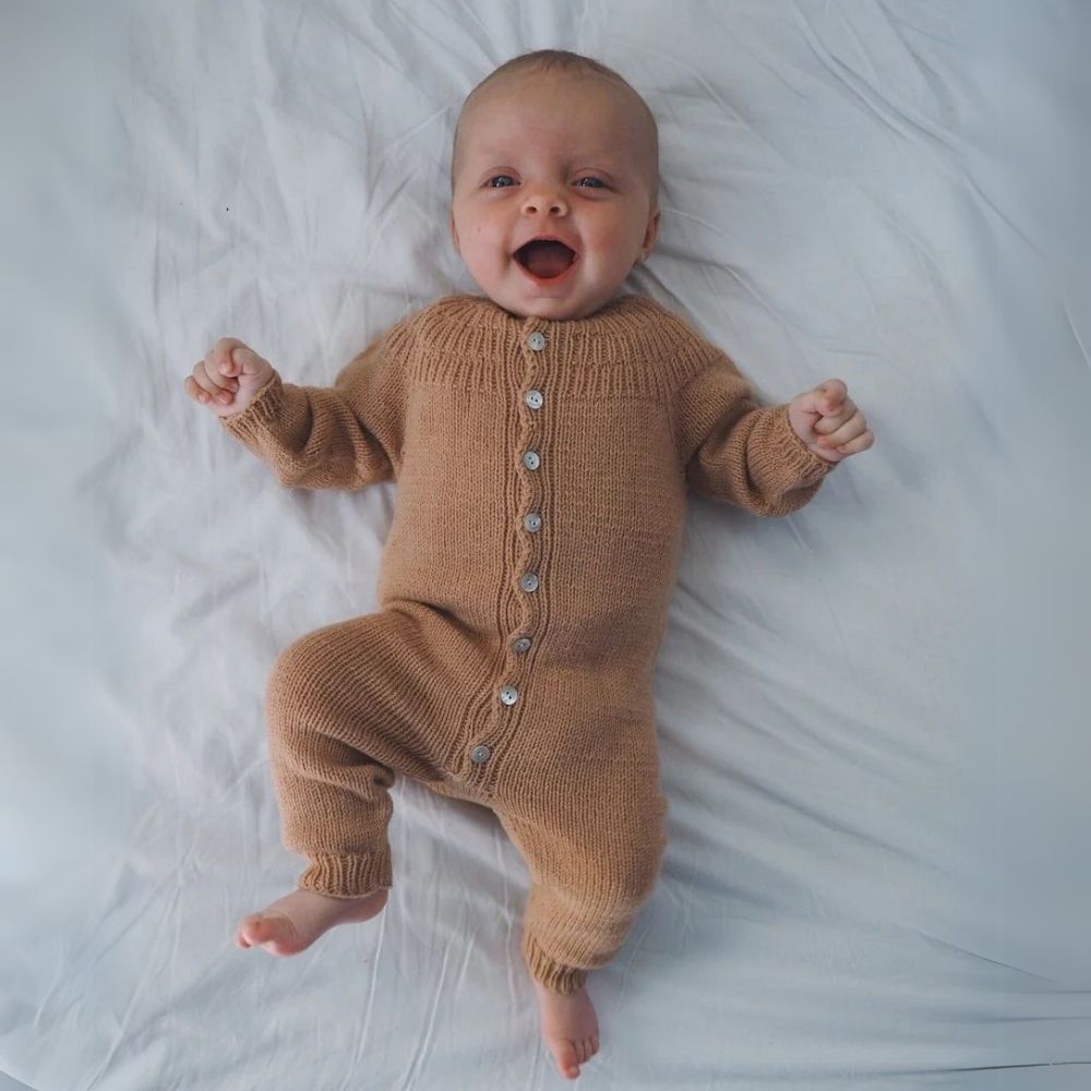 A joyful baby showcasing the charming design of Anker’s Onesie with its unique yoke and ribbed details.