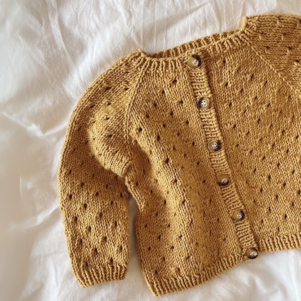 A summer cardigan with a delicate lace design and front holes, crafted from the top down for a stylish fit.