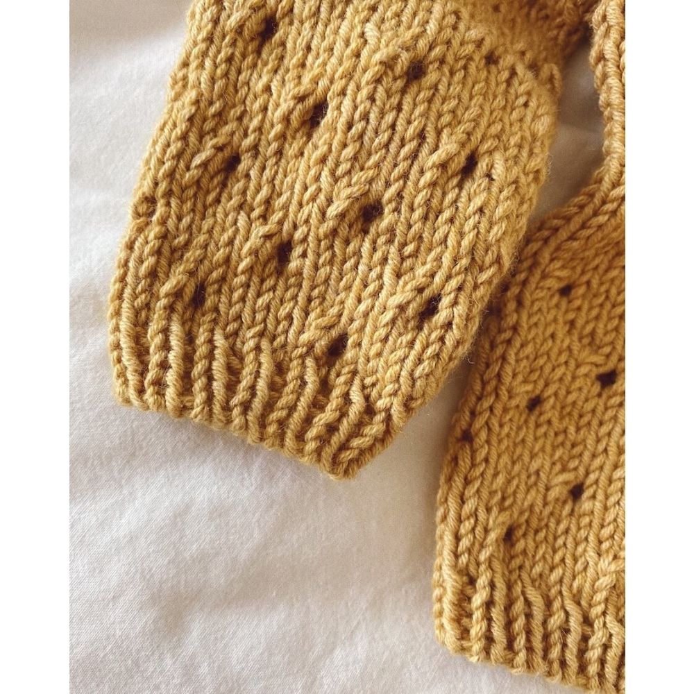 Detailed view of a knitted sweater with holes, highlighting the feminine lace pattern and top-down construction.