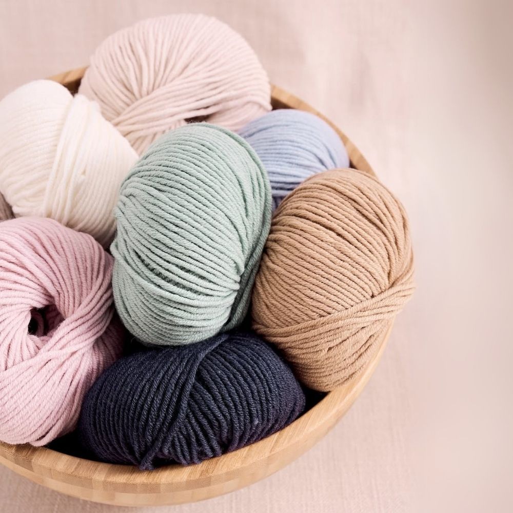 A basket with 7 balls of coloured yarns. Rowan-Mode-Merino-Soft