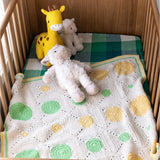Crocheted blanket with circular patterns in a crib with stuffed animals