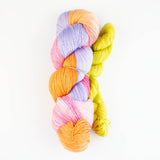 A skein of multicolor yarn with prominent orange, pink, purple, and green strands against a white background.