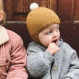 Baby dressed in warm knitted  Albert pilot hat and coat.