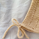 A stylish knitted hat with a knot, designed with ribbing and an i-cord edge, finished with two functional tie-strings.