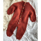 A knitted red baby onesie featuring buttons, designed with a circular yoke and ribbed plackets for easy dressing.