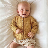 A baby in a yellow sweater and shorts, showcasing a cheerful summer outfit perfect for warm weather.