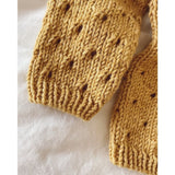 Detailed view of a knitted sweater with holes, highlighting the feminine lace pattern and top-down construction.