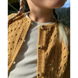 A young girl dressed in a yellow cardigan, highlighting a lovely lace pattern and neatly finished button edges.