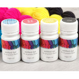 Four vibrant yarn bottles—turquoise, bright pink, bright yellow, and coal—next to a bottle of ink for creative dyeing.
