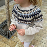 A blue and brown patterned sweater featuring a circular yoke and ribbed edges, showcasing intricate colorwork design.
