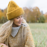 model smiling wearing a yellow hat and a sweater