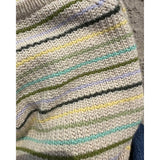 Detailed view of a striped knitted sweater, highlighting the ribbed neck edge and the texture of the broken rib pattern.