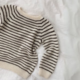 friday sweater displayed on a bed, emphasizing its broken rib texture and ribbed edges for a stylish look.
