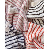 A vibrant assortment of striped sweaters in different colors, stacked together, highlighting their unique patterns.