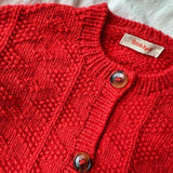 A red button-up sweater showcasing a textured design, crafted with a ribbed neck and detailed plackets.