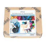 A spinning kit for beginners, including hand carders, a drop spindle, various fibers, and step-by-step instructions in a box.