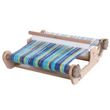A compact wooden loom displaying blue and green stripes, designed for both new and experienced weavers to create samples.
