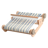 A compact wooden loom displaying blue and white stripes, designed for both new and experienced weavers to create samples.